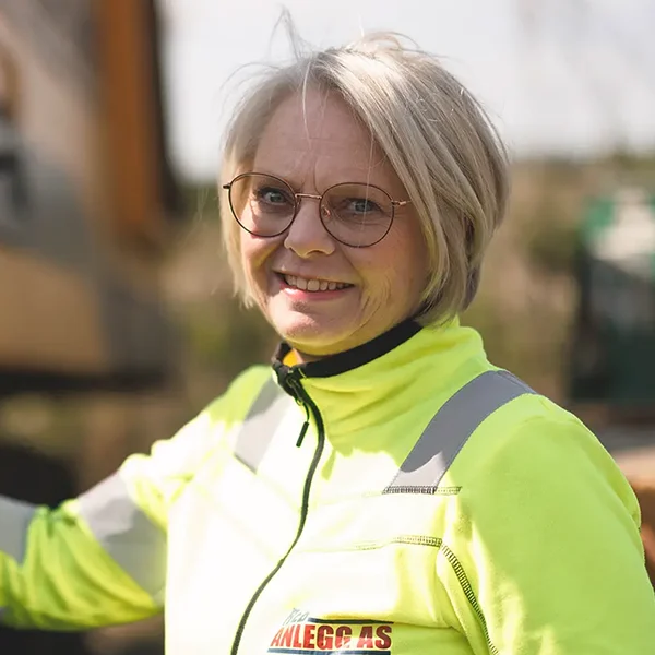 En kvinne i gul jakke står ved siden av en Kontakt-lastebil.