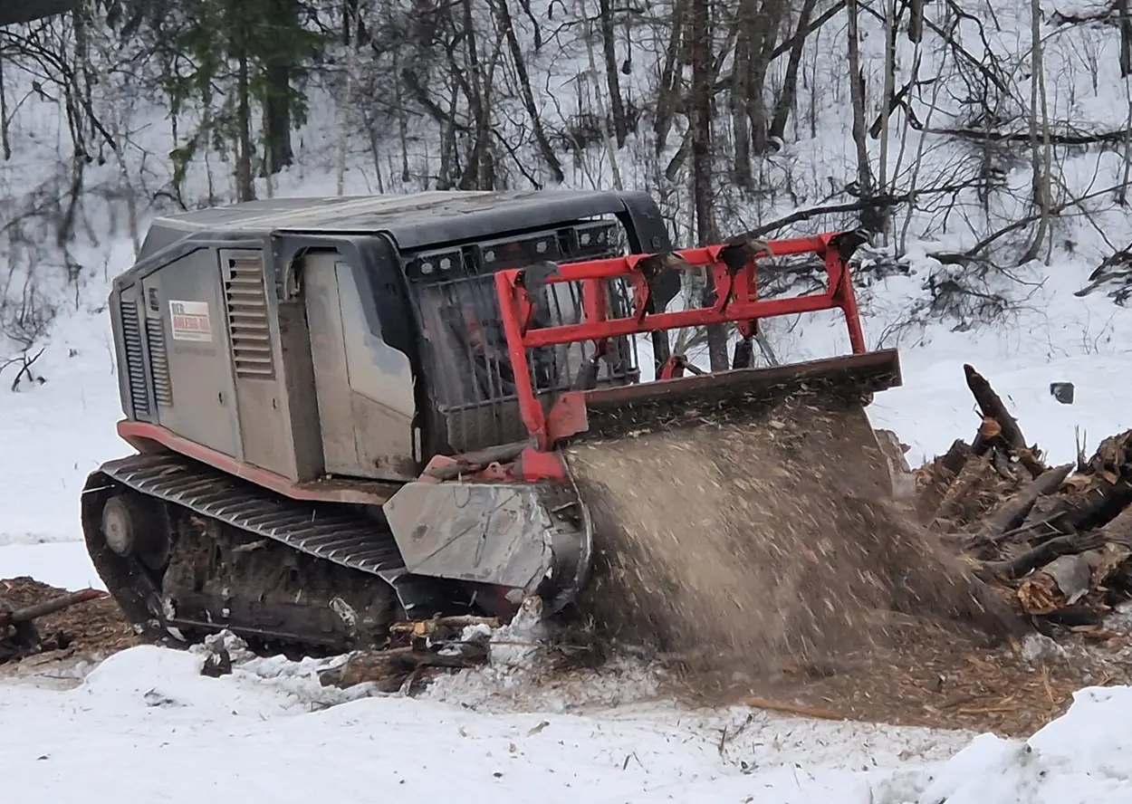 En bulldoser rydder et snødekt område med en bulldoser.