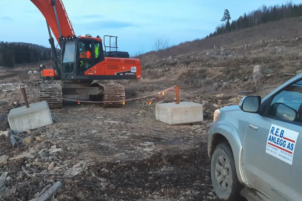 En Skanska gravemaskin jobber på en grusvei.