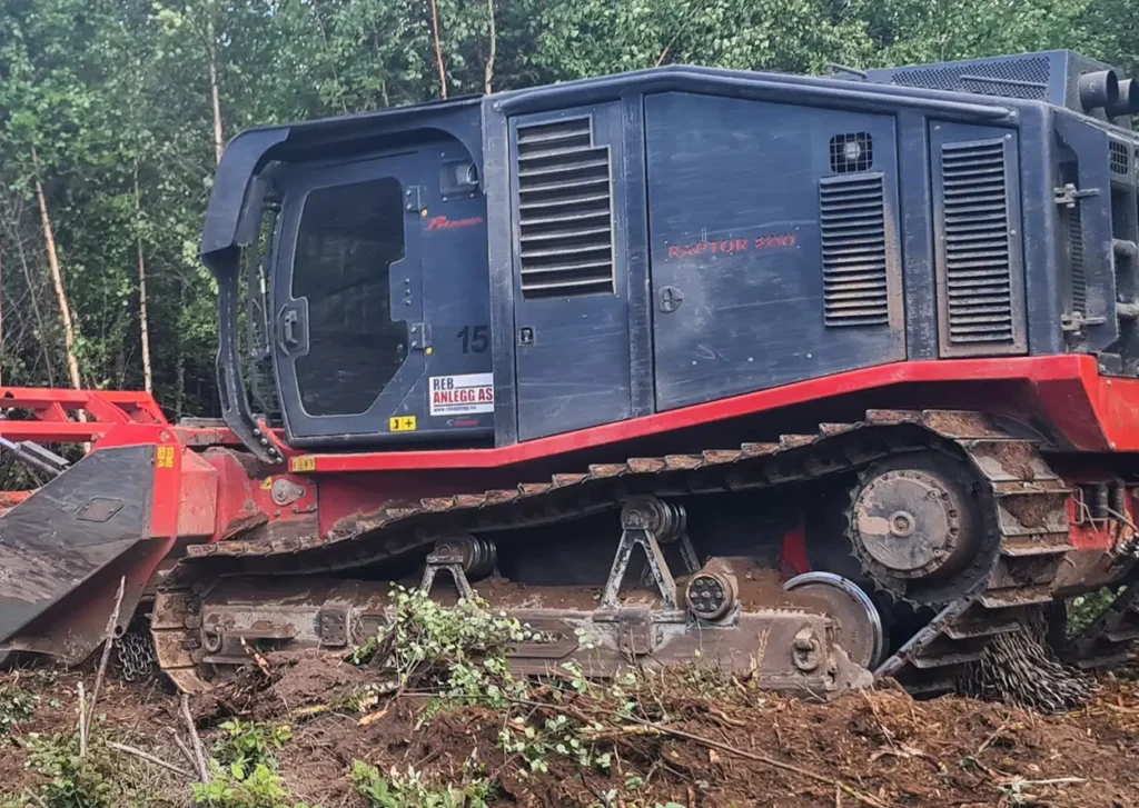 En rød og blå bulldoser i skogen.