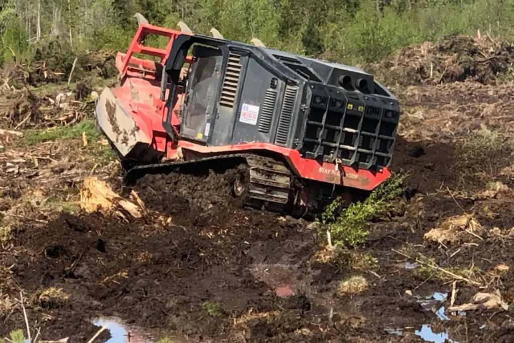 En rød bulldoser i et gjørmete område på en gård.