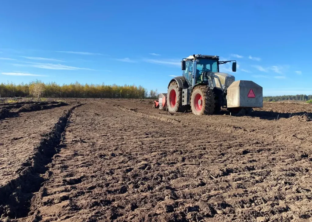 En traktor som jobber midt på et jorde og styrer brøyteoperasjonene.