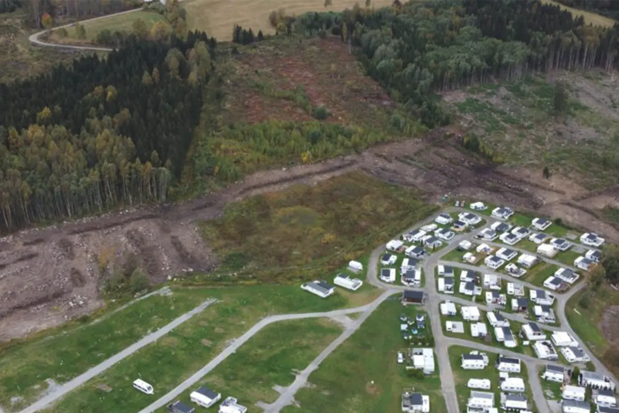 En luftfoto av en skogkledd bobilpark med frodig vegetasjon rundt campingplassen.