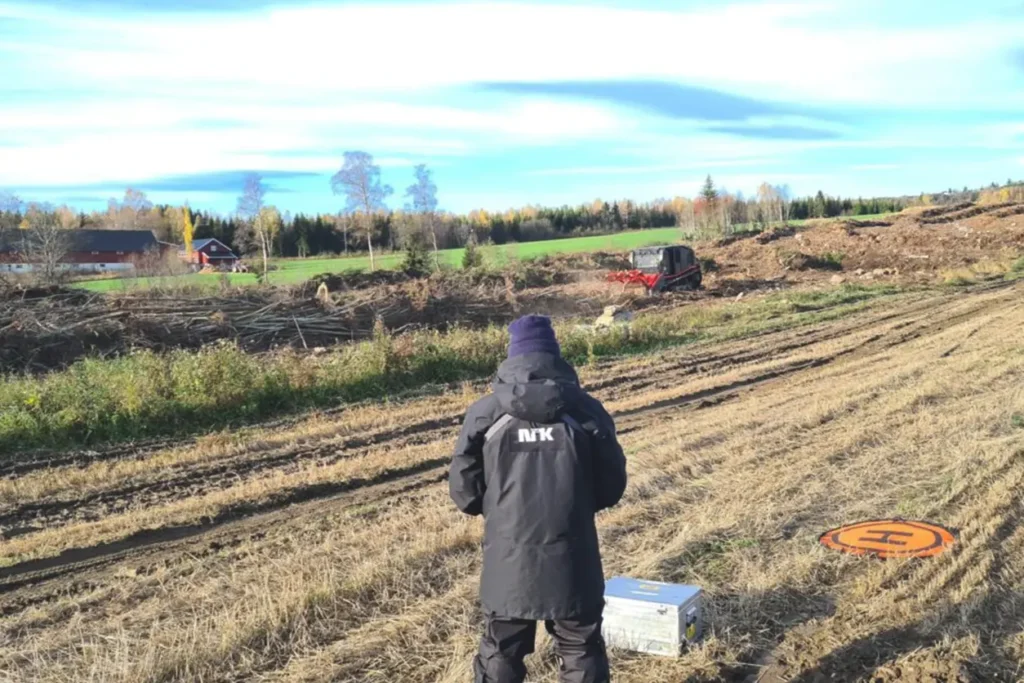 En mann står i en park og ser på en gjenstand.