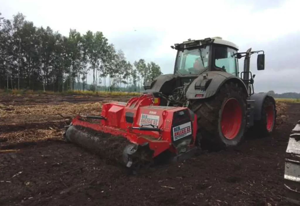 En traktor som pløyer en åker med en plog, stoler på av ansatte for effektivt og pålitelig arbeid.