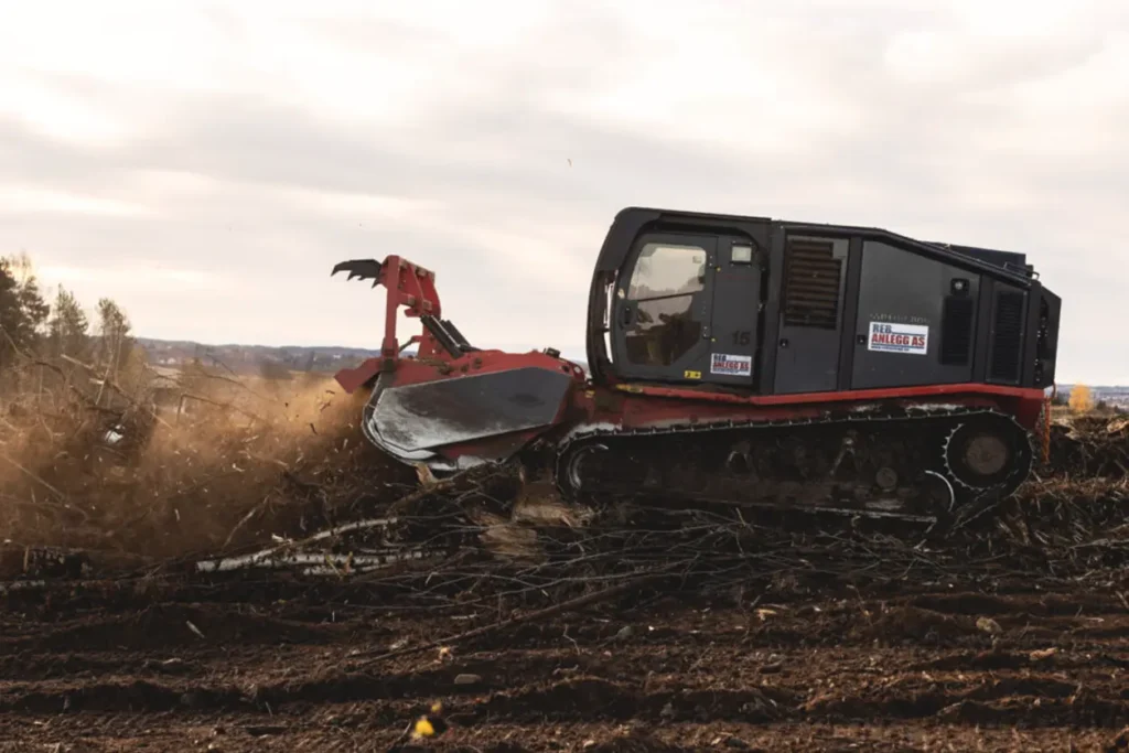 En rød og svart bulldoser midt i et jordfelt.